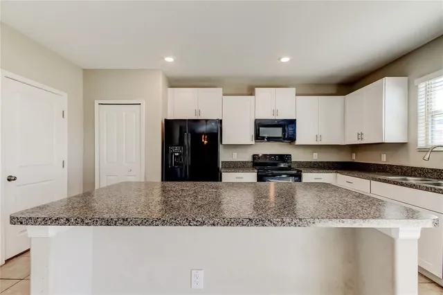 a kitchen with stainless steel appliances granite countertop a sink and a refrigerator