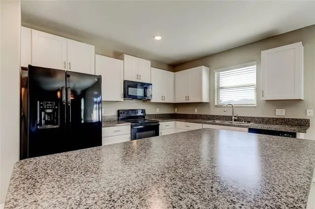 a kitchen with granite countertop cabinets a sink and appliances