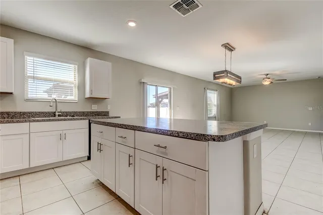 a view of an empty room with window and chandelier fan