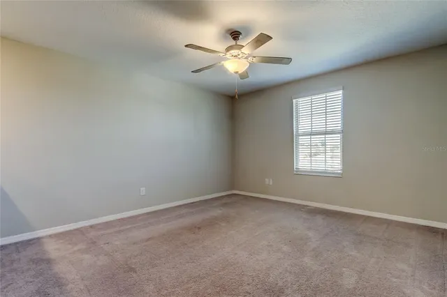 an empty room with windows and fan