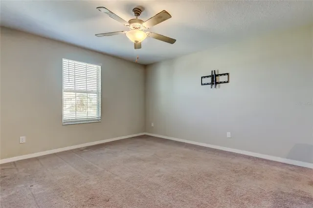an empty room with a ceiling fan and a window