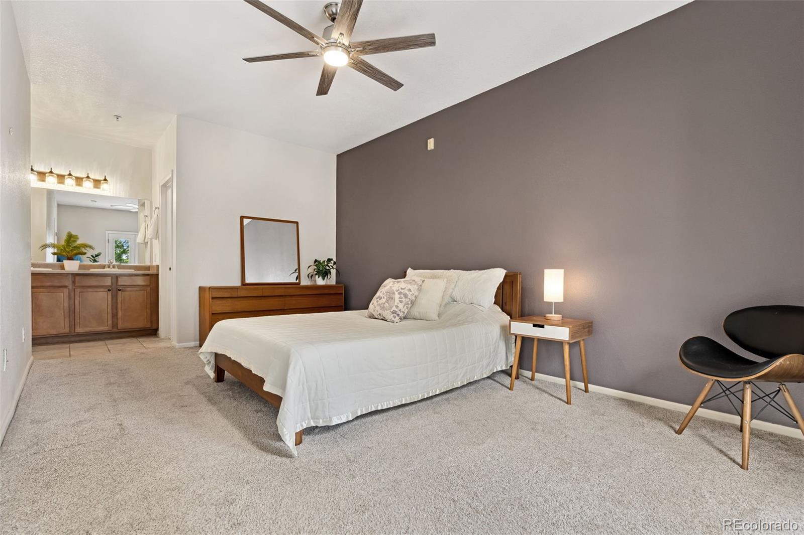 7140 Simms Street, Unit 102 Arvada, CO 80004 - Photo 18 of 34 a spacious bedroom with a bed and a lamp