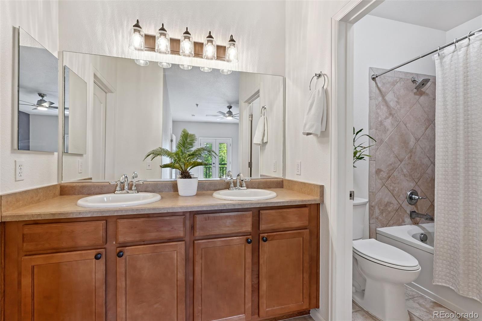 7140 Simms Street, Unit 102 Arvada, CO 80004 - Photo 20 of 34 a bathroom with a granite countertop sink a toilet a mirror a vanity and shower