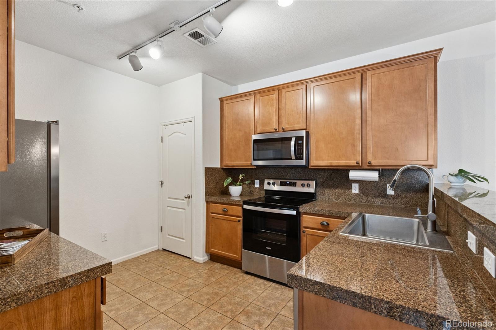 7140 Simms Street, Unit 102 Arvada, CO 80004 - Photo 9 of 34 a kitchen with stainless steel appliances granite countertop a stove top oven a sink and a granite counter tops