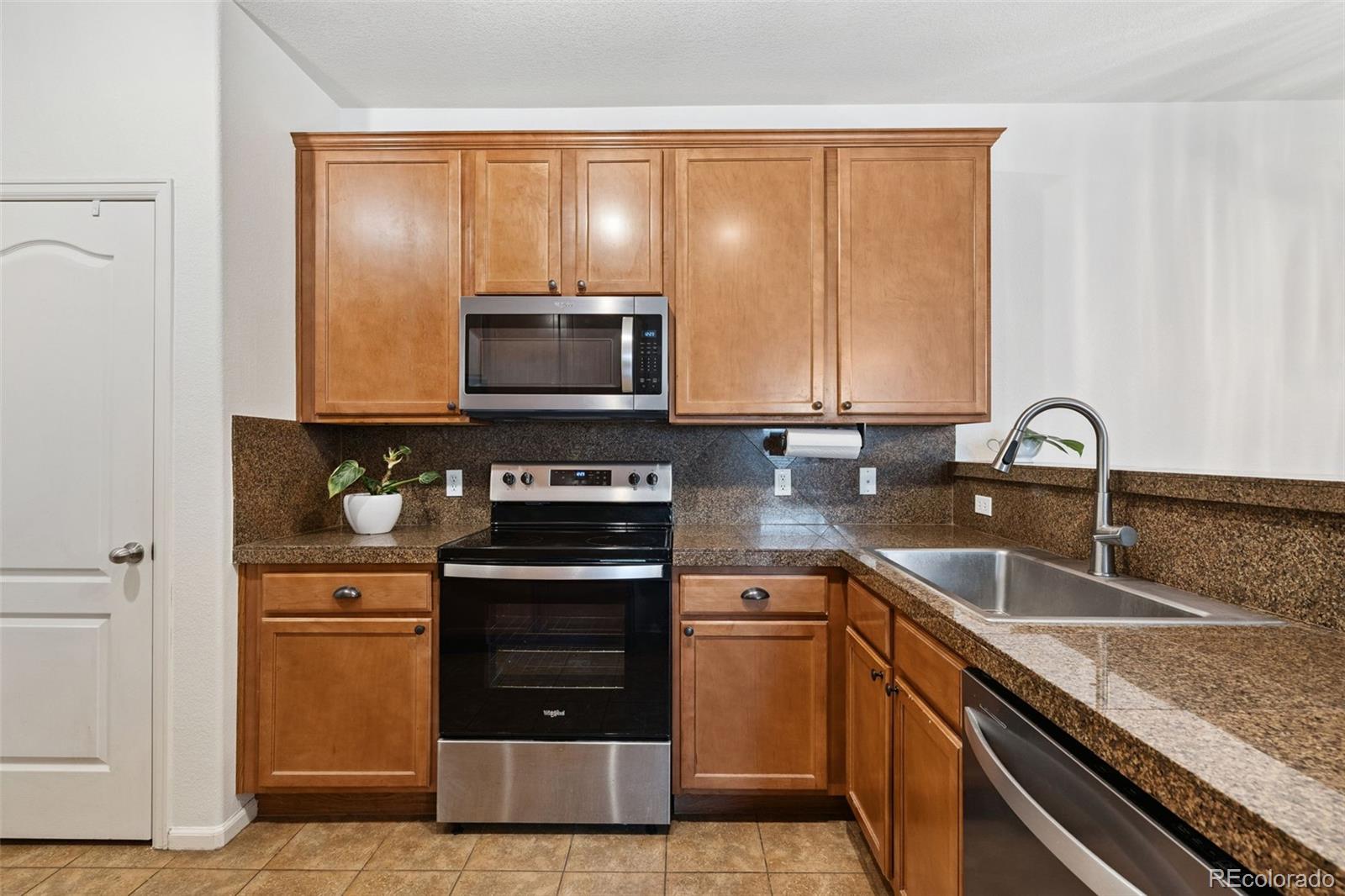 7140 Simms Street, Unit 102 Arvada, CO 80004 - Photo 10 of 34 a kitchen with stainless steel appliances granite countertop a stove a sink and a microwave