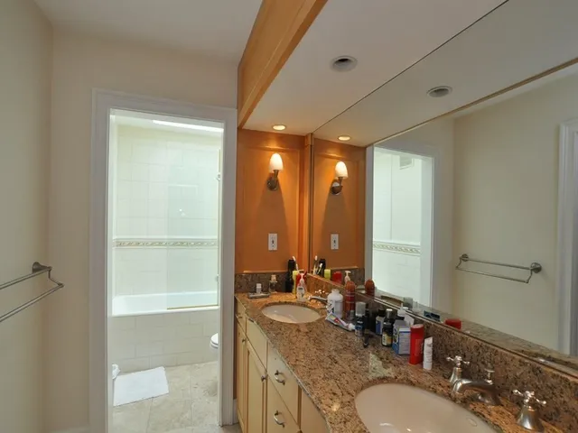 a bathroom with a granite countertop sink a mirror and a shower