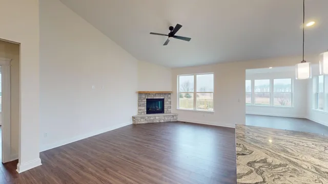 an empty room with wooden floor fireplace and windows