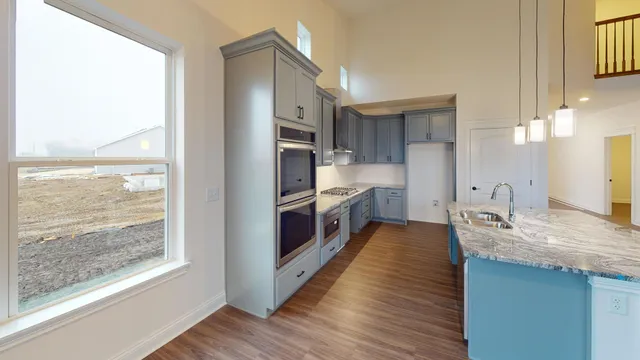 a large kitchen with granite countertop a large counter top a sink stainless steel appliances and cabinets