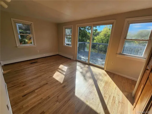 a view of an empty room with wooden floor and windows