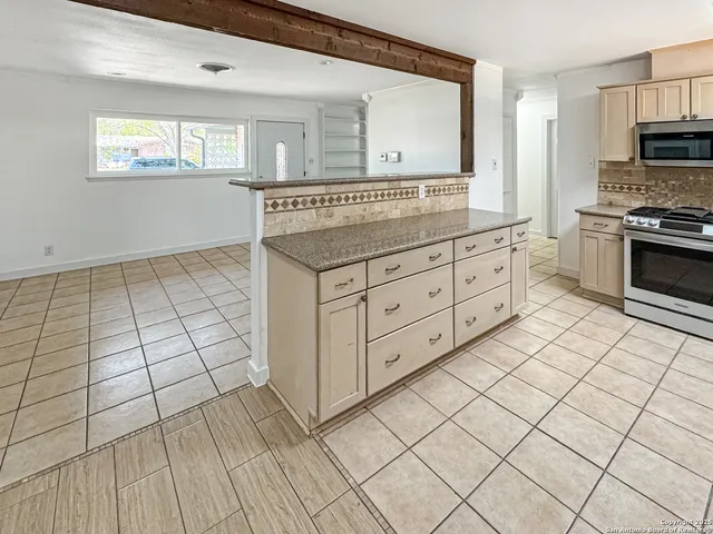a kitchen with granite countertop a stove sink and microwave