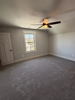 an empty room with windows and fan