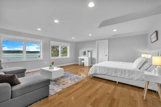 a spacious bedroom with a bed couch and wooden floor