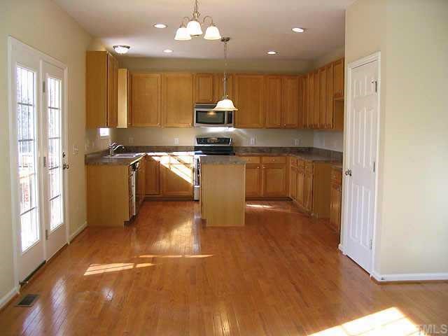 1256 Magnolia Hill Road Garner, NC 27529 - Photo 5 of 10 a kitchen with kitchen island granite countertop wooden floors and a view of living room