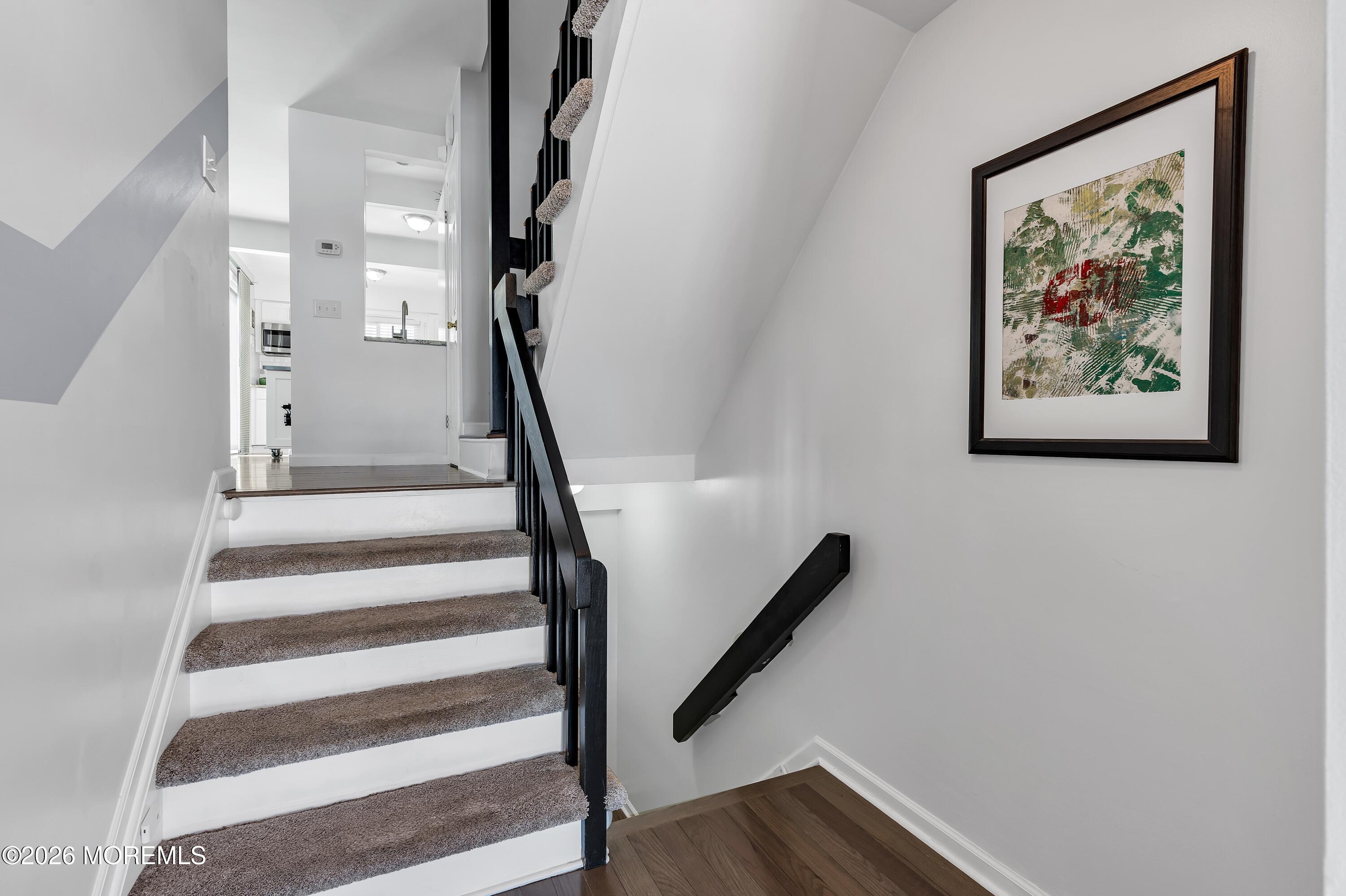 580 Patten Avenue, Unit 14 Long Branch, NJ 07740 - Photo 28 of 29 a view of staircase with wooden floor and lots of frames on wall