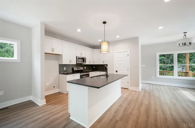 a kitchen with kitchen island a sink a stove a refrigerator and white cabinets with wooden floor