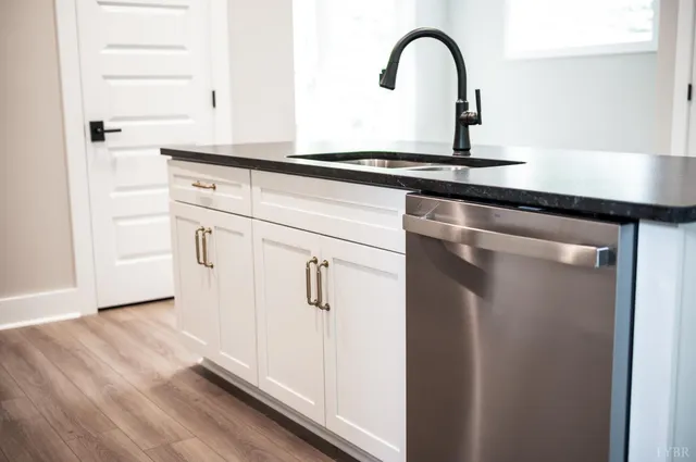 a close view of a sink and dishwasher with wooden floor