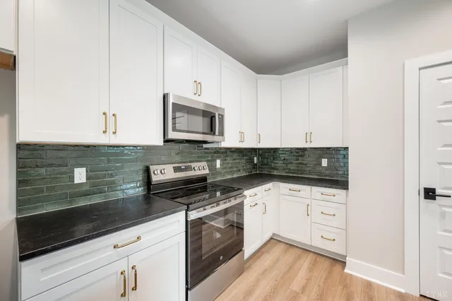 a kitchen with white cabinets stainless steel appliances and wooden floor
