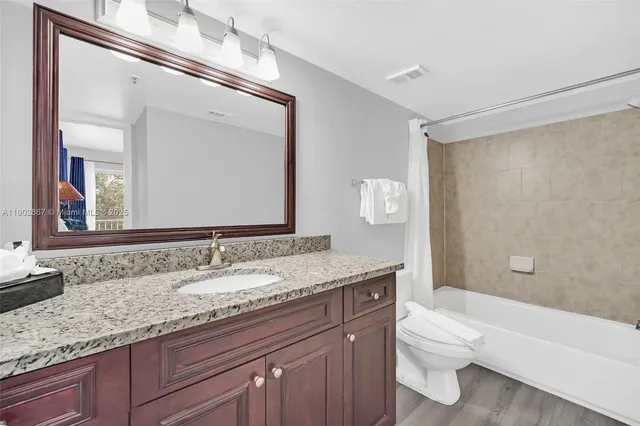 a bathroom with a granite countertop sink a toilet and a mirror