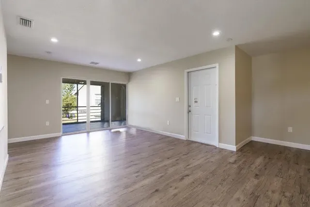 a view of an empty room with wooden floor and a window