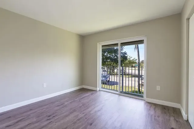 a view of an empty room with wooden floor and a window