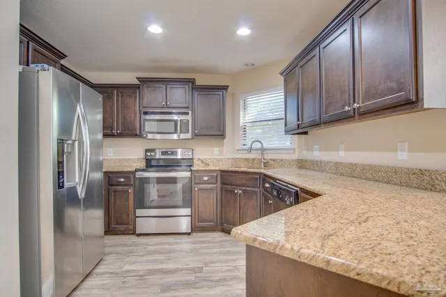 a kitchen with kitchen island granite countertop wooden cabinets stainless steel appliances and a sink