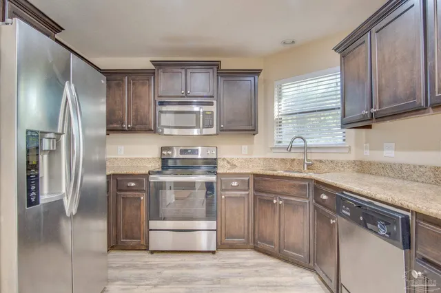 a kitchen with stainless steel appliances granite countertop a sink stove refrigerator and cabinets
