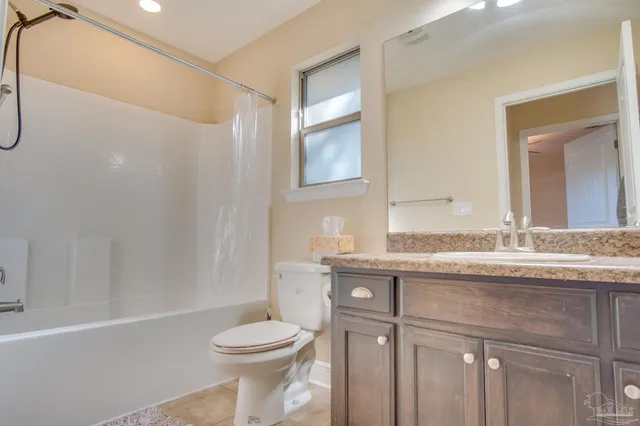 a bathroom with a granite countertop sink a toilet and a mirror