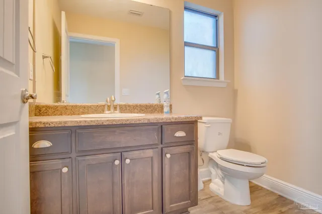 a bathroom with a granite countertop toilet sink and mirror