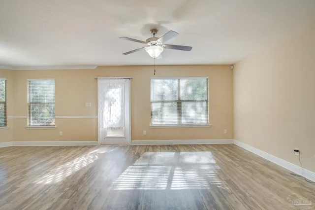 an empty room with wooden floor and windows