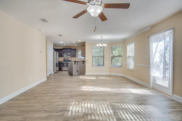 a view of an empty room with window and a kitchen