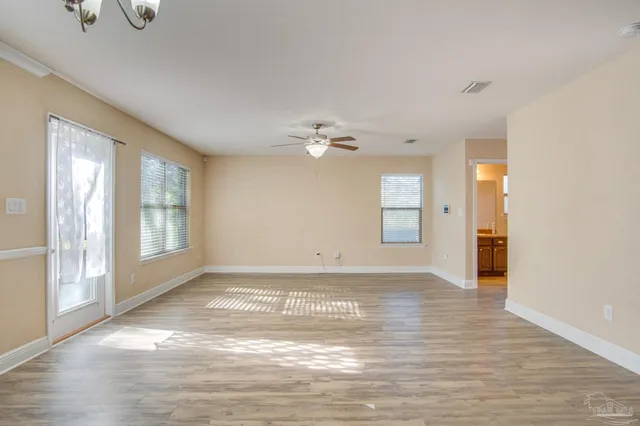 a view of an empty room with window and wooden floor