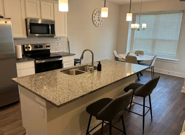 a kitchen with granite countertop sink table and chairs