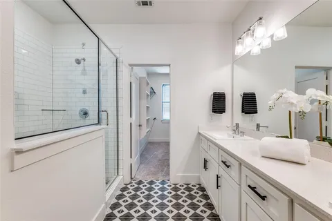 a spacious bathroom with a double vanity sink a large mirror and shower