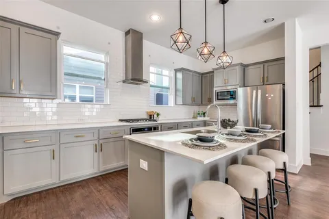 a kitchen with stainless steel appliances kitchen island granite countertop a sink a stove a dining table and chairs