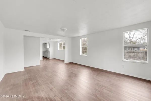 a view of an empty room with wooden floor and a window