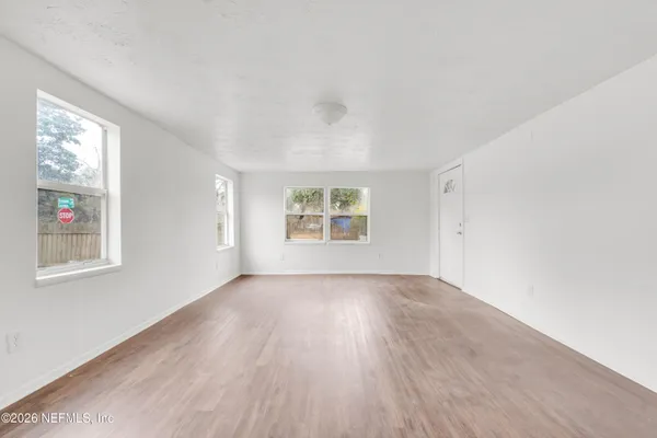 an empty room with wooden floor and windows