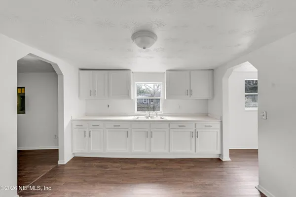 a large white kitchen with wooden floor and a sink