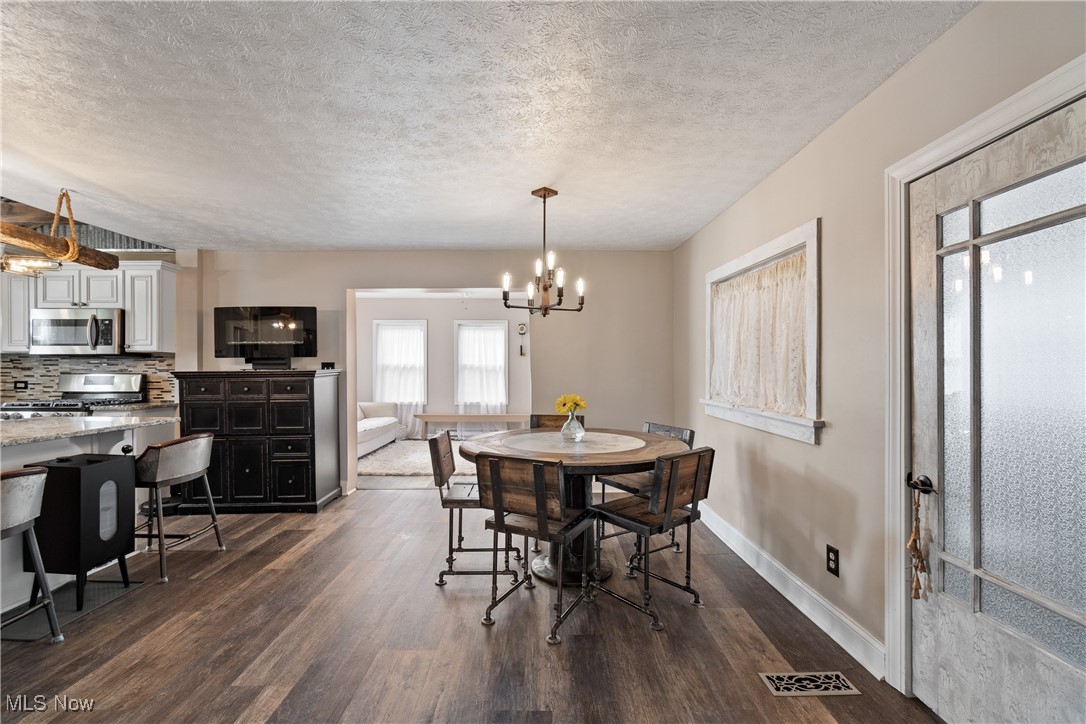 4786 Mayfair Road North Canton, OH 44720 - Photo 8 of 38 Dining space with dark wood finished floors, a textured ceiling, and a chandelier