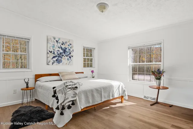 a bedroom with a bed a table and windows