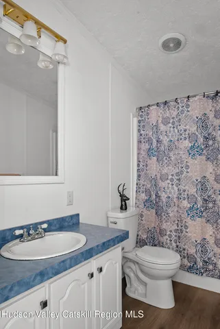 a bathroom with a granite countertop toilet a sink and a mirror
