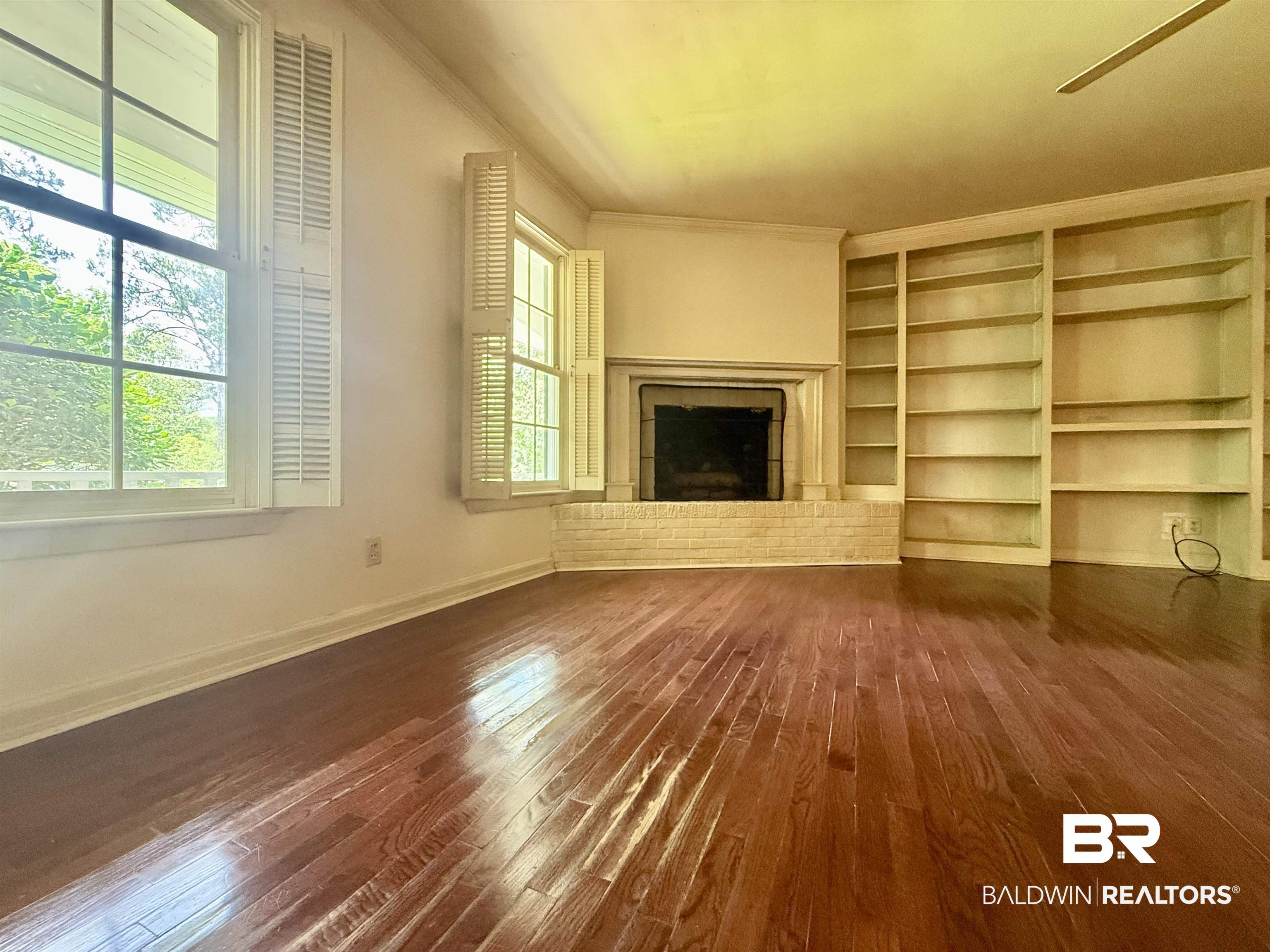 1412 Poplar Avenue Brewton, AL 36426 - Photo 14 of 32 Unfurnished living room featuring dark wood-type flooring, a fireplace, baseboards, ornamental molding, and built in features