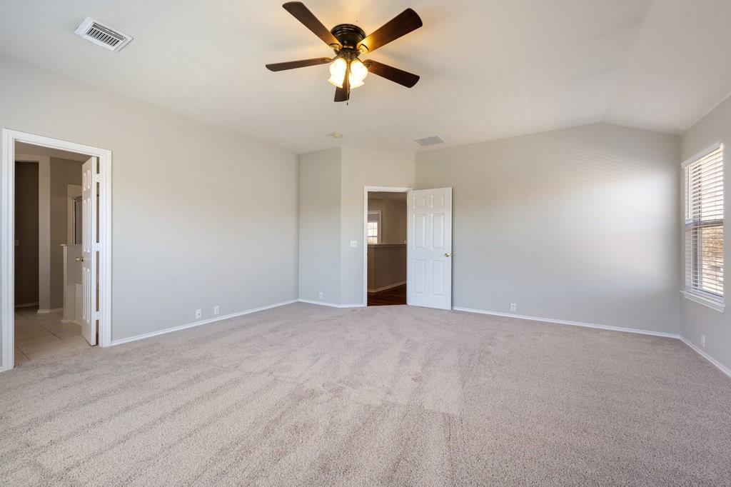 1216 Mathias Street Cedar Park, TX 78613 - Photo 9 of 16 Unfurnished bedroom with ceiling fan, light carpet, ensuite bath, and vaulted ceiling