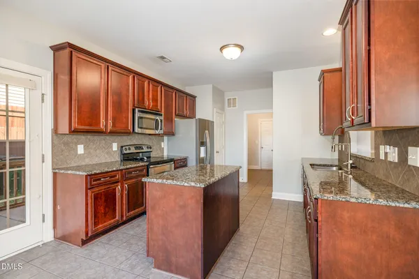 a large kitchen with stainless steel appliances granite countertop a sink and cabinets