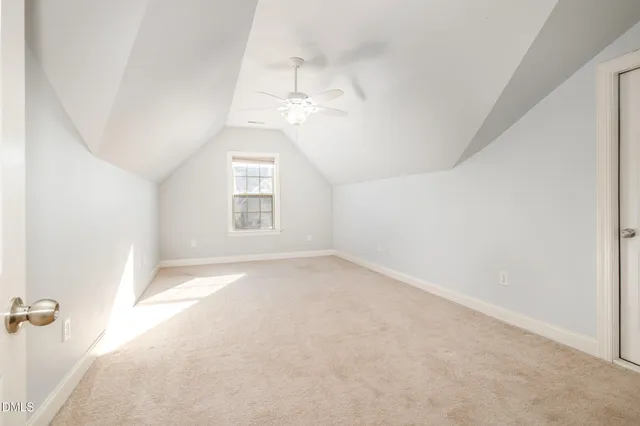 an empty room with a chandelier fan and windows