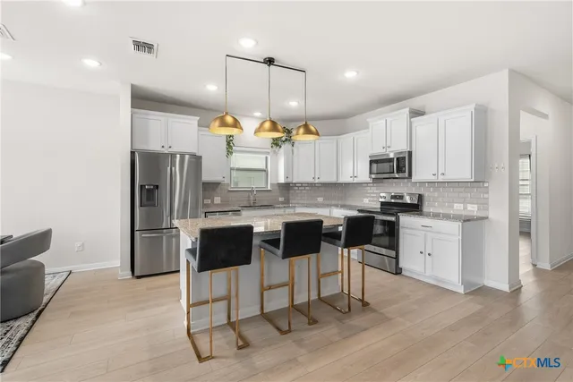 a kitchen with kitchen island granite countertop wooden cabinets and a view of living room