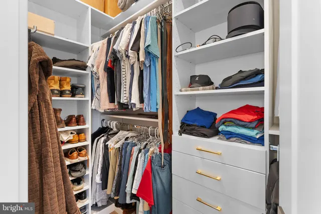 a view of walk in closet with clothes and shoes