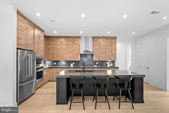 a kitchen with stainless steel appliances granite countertop a sink a stove a refrigerator counter tops chairs and a refrigerator