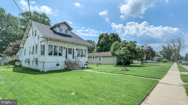 a view of a house with a big yard and large trees