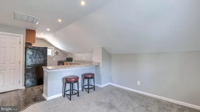 a room with kitchen island stainless steel appliances a sink and a refrigerator