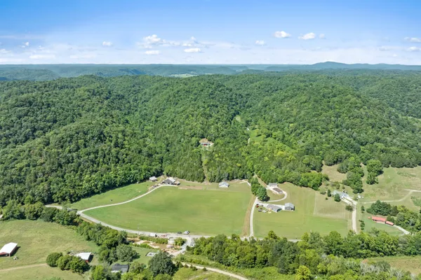 an aerial view of a house with a yard and trees all around